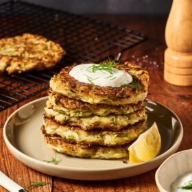 stack of zucchini fritters topped with sour cream