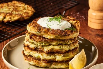 stack of zucchini fritters topped with sour cream