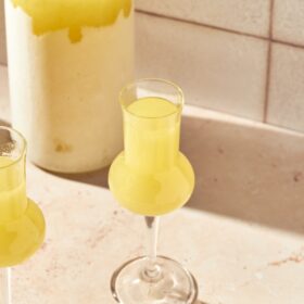 glass of limoncello next to a limoncello bottle
