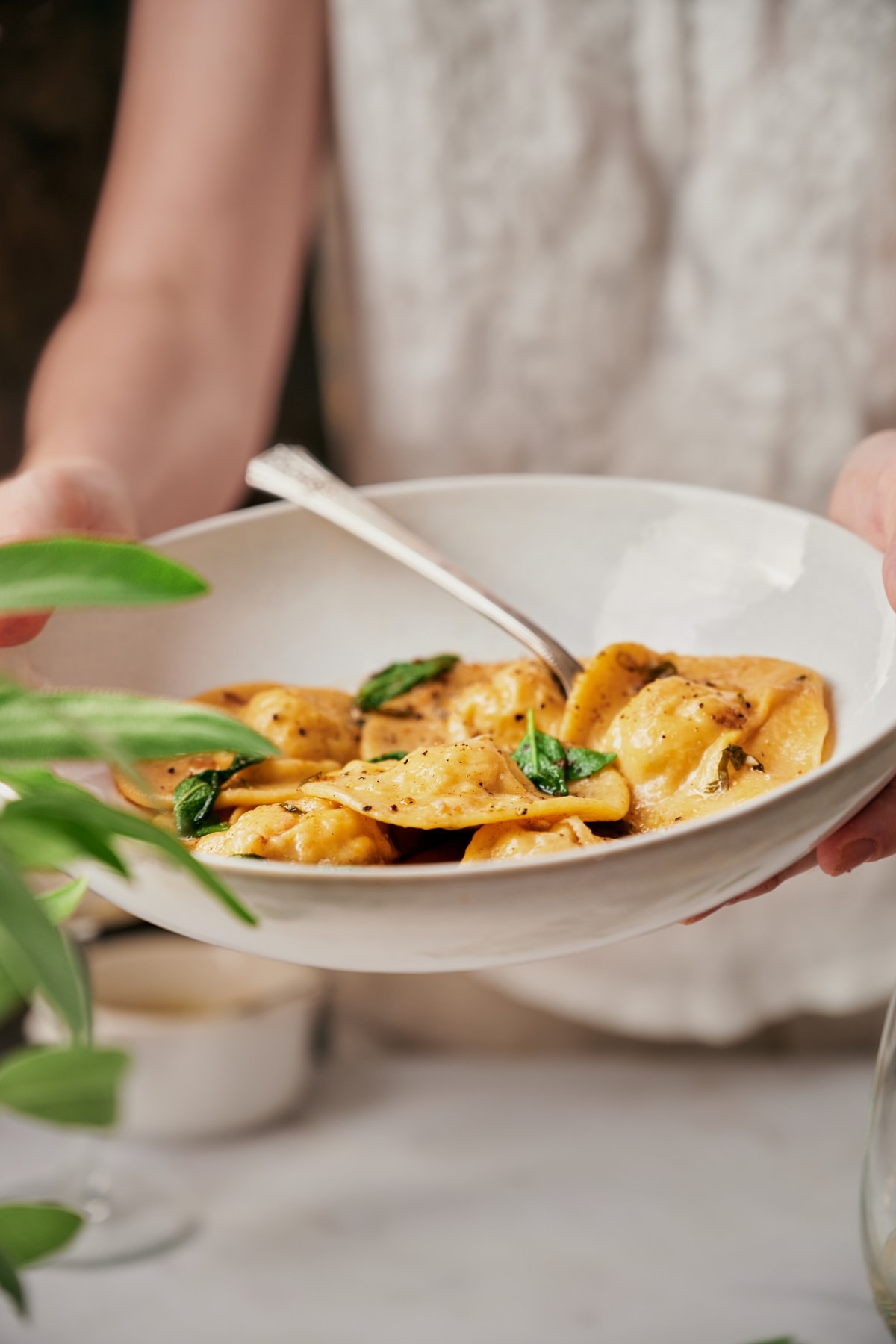 Hands holding a plate of Lobster Ravioli.