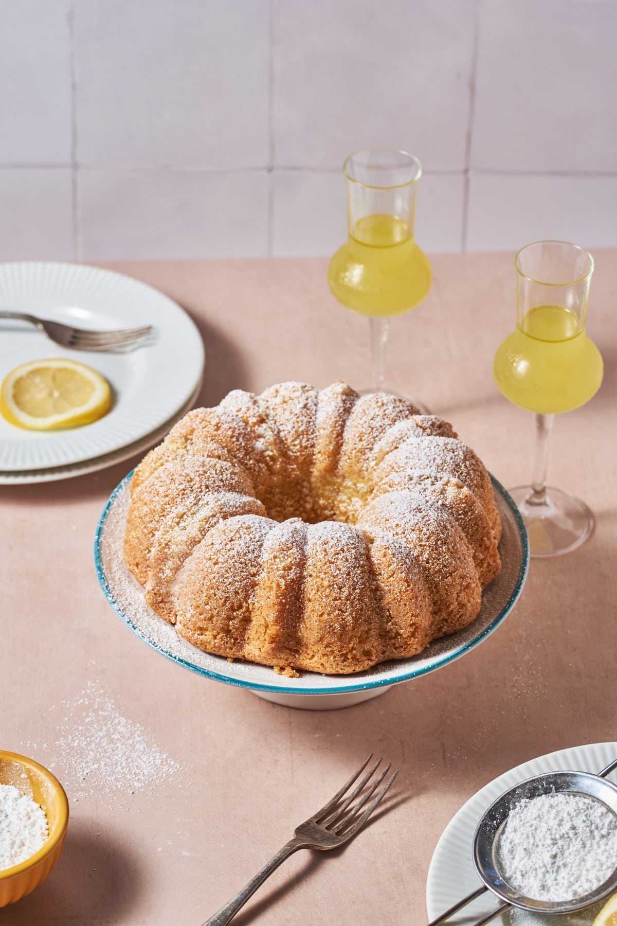 limoncello cake on a plate beside some glasses of limoncello