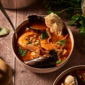 a bowl of cioppino soup with a piece of bread