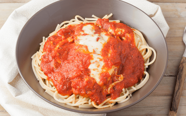 a beatiful plate of chicken parmigiana over spaghetti pasta