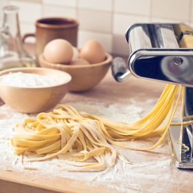 homemade fresh pasta and pasta machine on kitchen table